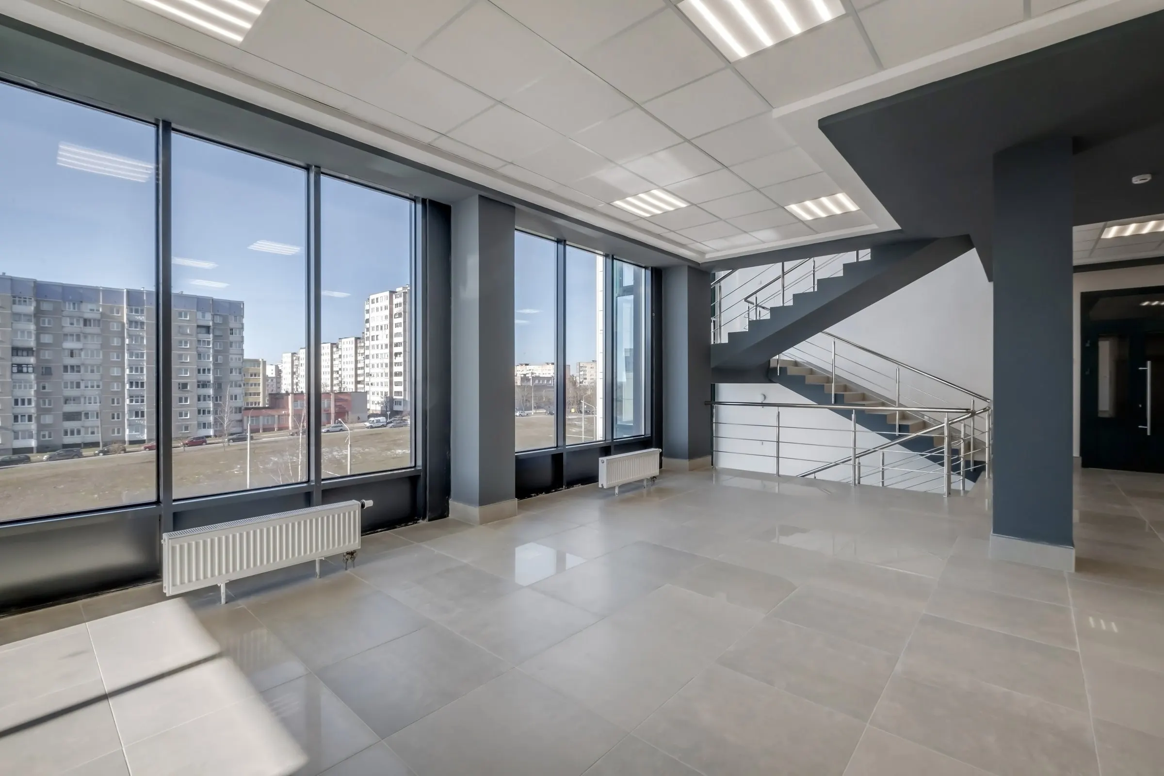 Leere Gewerbefläche mit großen Fenstern und offener Treppe